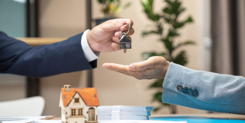 Estate agent giving house keys to woman and sign agreement in office